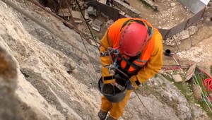 Turisti na brale obdivujú murárov zavesených na lanách