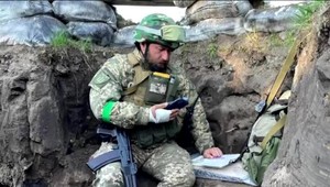 Ukrajinský profesor sedí so zbraňou na kolene v zákope a prednáša svojim študentom