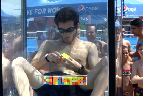 mladík pod vodou skladá Rubikovu kocku