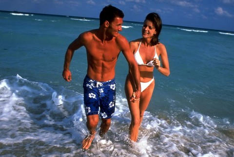 Pláž dovolenka muž so ženou v plavkách behajú pri mori