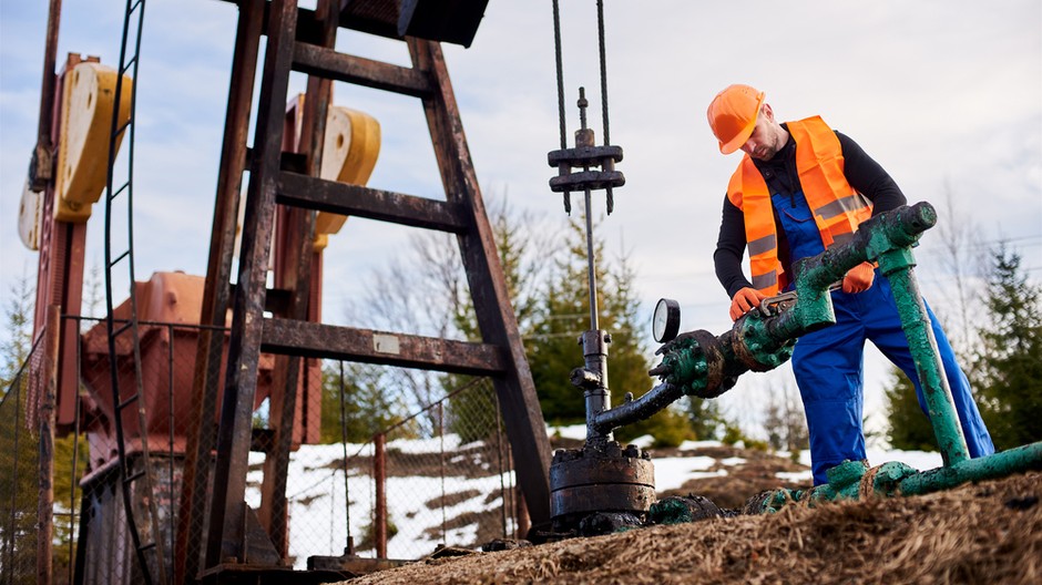 oil-worker-orange-uniform-helmet-working-with-pipe-wrench-near-oil-pump-jack