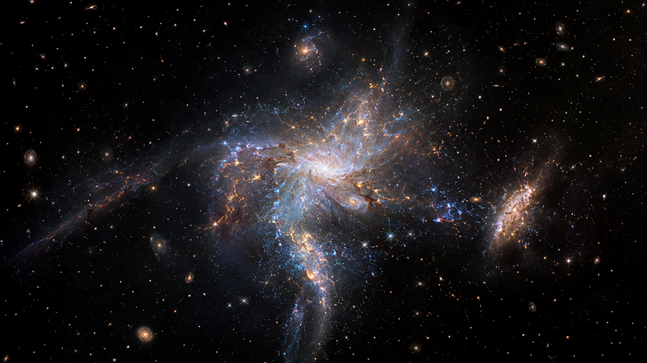 Masívna mladá galaxia obklopená menšími galaxiami v ranom vesmíre zachytená v štýle pozorovaní teleskopu Jamesa Webba.