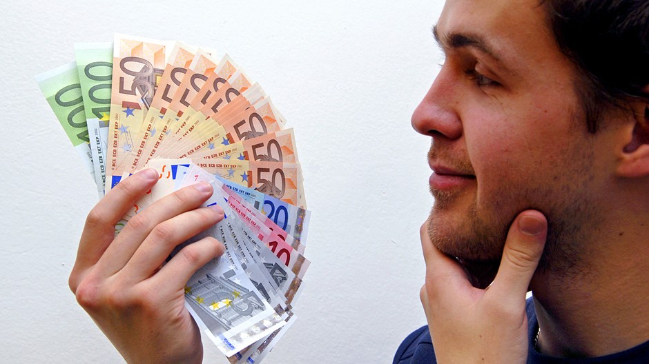 Muž mladík drží peniaze