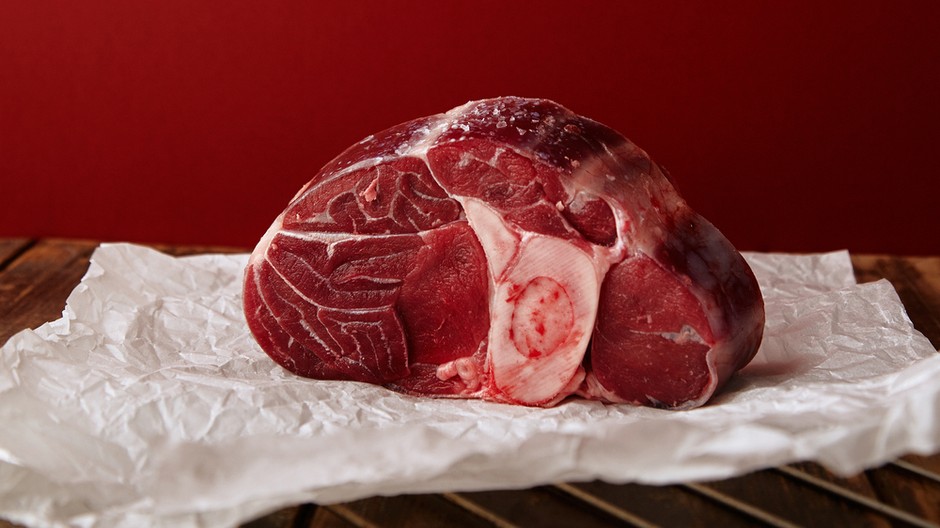 presentation-angus-leg-steak-wooden-table-red-wall