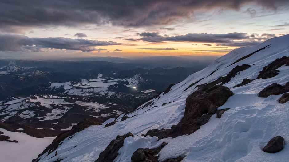 Hora na zasneženom svahu Mount Shasta počas náročného zostupu za súmraku.