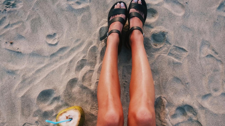 Opálené ženské nohy na piesočnatej pláži