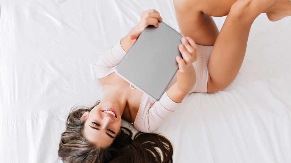 from-pretty-brunette-girl-bed-with-tab-hands-she-has-long-hair-smiling 