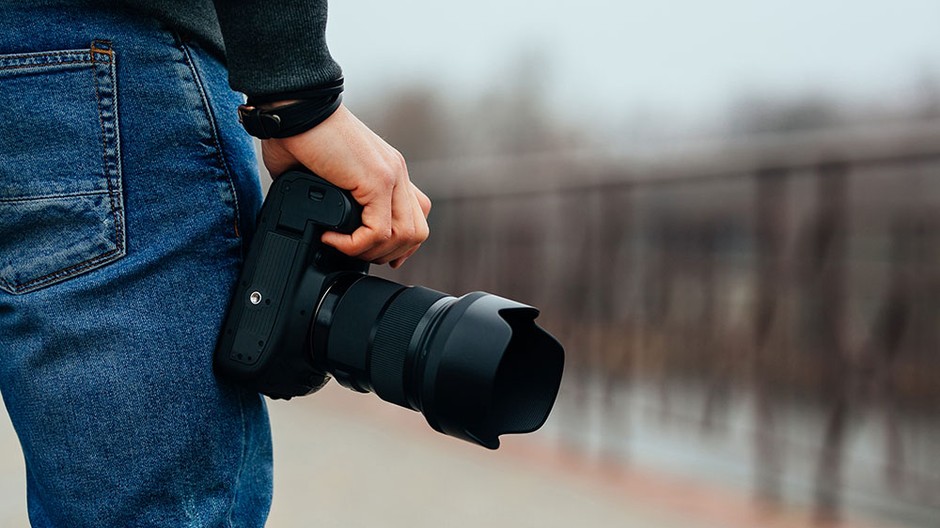 close-up-view-of-male-hand-holding-professional-camera-on-the-street