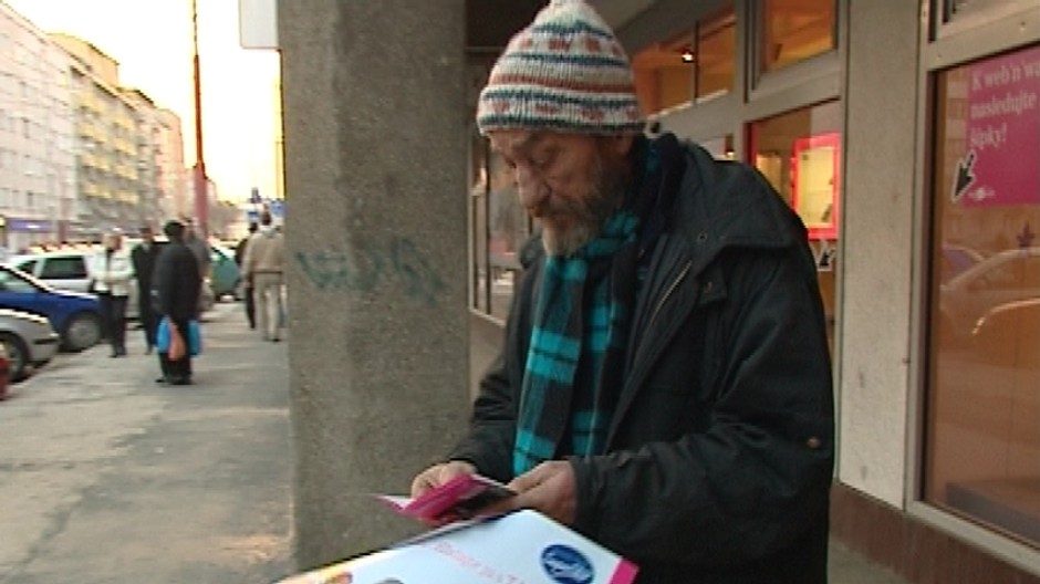 bezdomovec pred obchodom pozera v rukach letaky