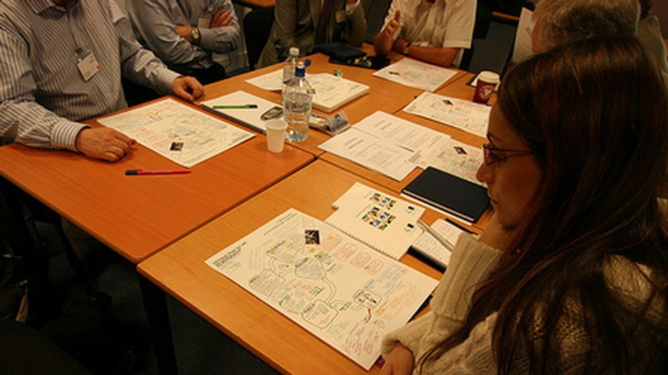 ľudia za stolíkom, na stole papiere-konferencia