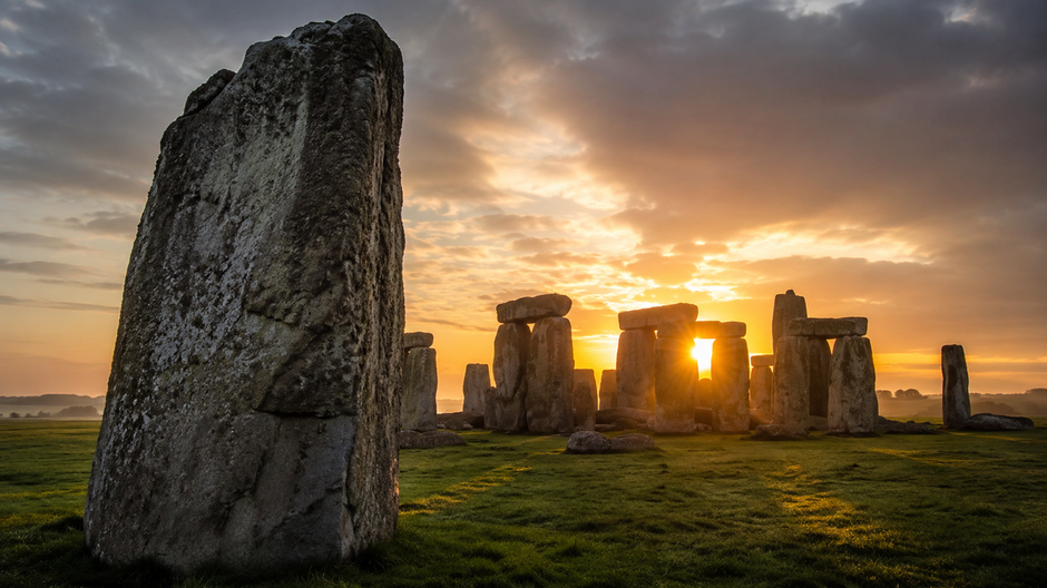 Stonehenge počas východu slnka s dominantným kamenným blokom v popredí.