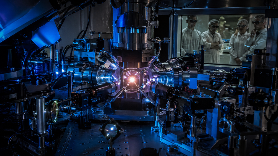 Vedci sledujú žiariaci cieľ v laserovej fúznej komore počas experimentu v štýle dokumentárnej fotografie.