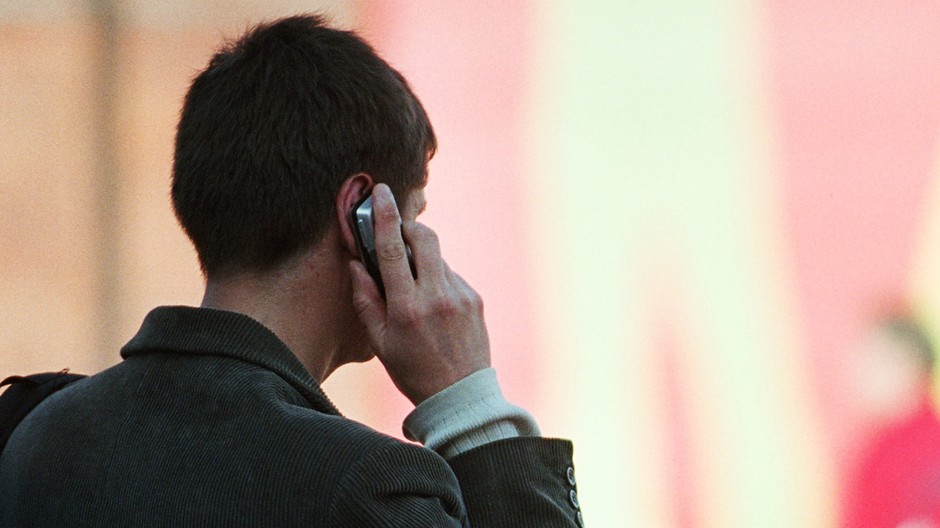 Muž telefonuje telefón zozadu v ruke